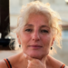 Zelfbewuste vijftigplus vrouw met een eigen signature kledingstijl glimlacht in de camera