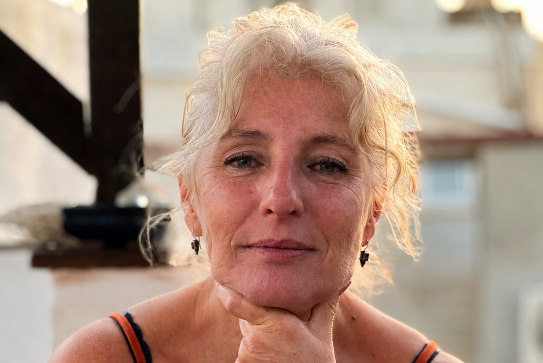 Zelfbewuste vijftigplus vrouw met een eigen signature kledingstijl glimlacht in de camera